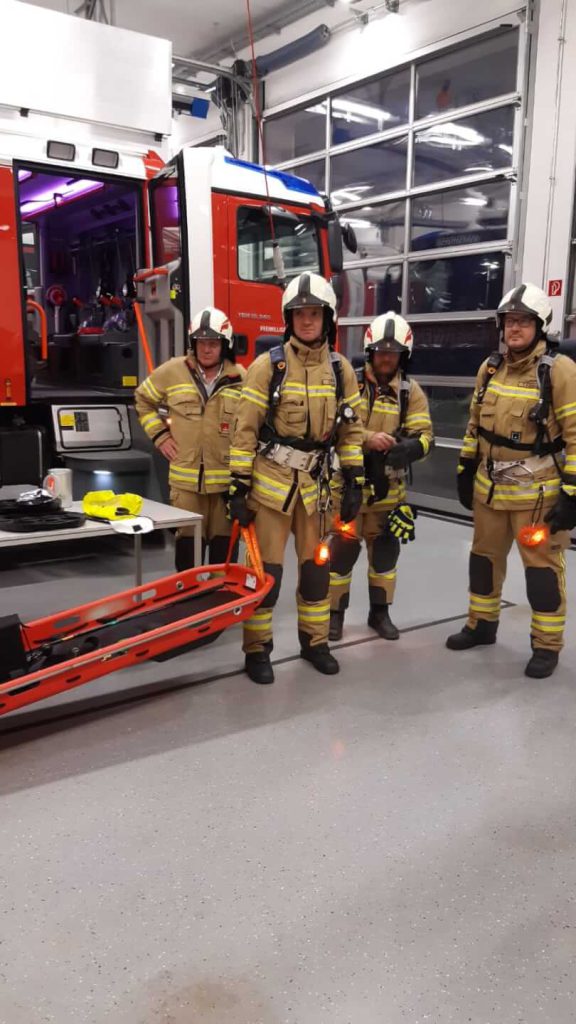 Vier Feuerwehrleute Maishofen in Schutzausrüstung bei Tunnelausbildung neben Einsatzfahrzeug