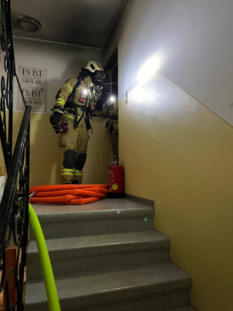 Atemschutzträger der Feuerwehr Maishofen bei Einsatz im Stiegenhaus mit Schlauch und Feuerlöscher