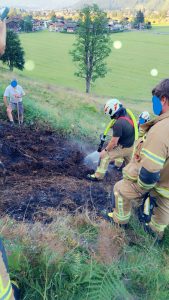 Feuerwehr löscht Flächenbrand am Hang mit Löschschlauch und Ausrüstung