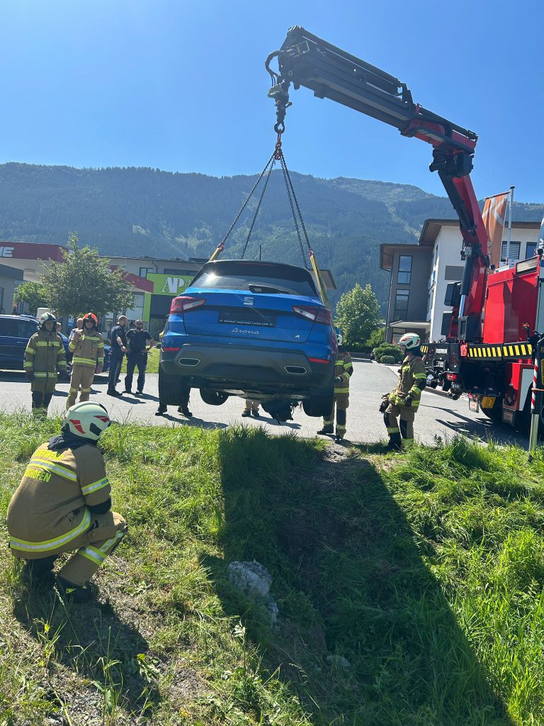 Feuerwehr hebt verunfalltes Auto mit Kran auf Straße zurück