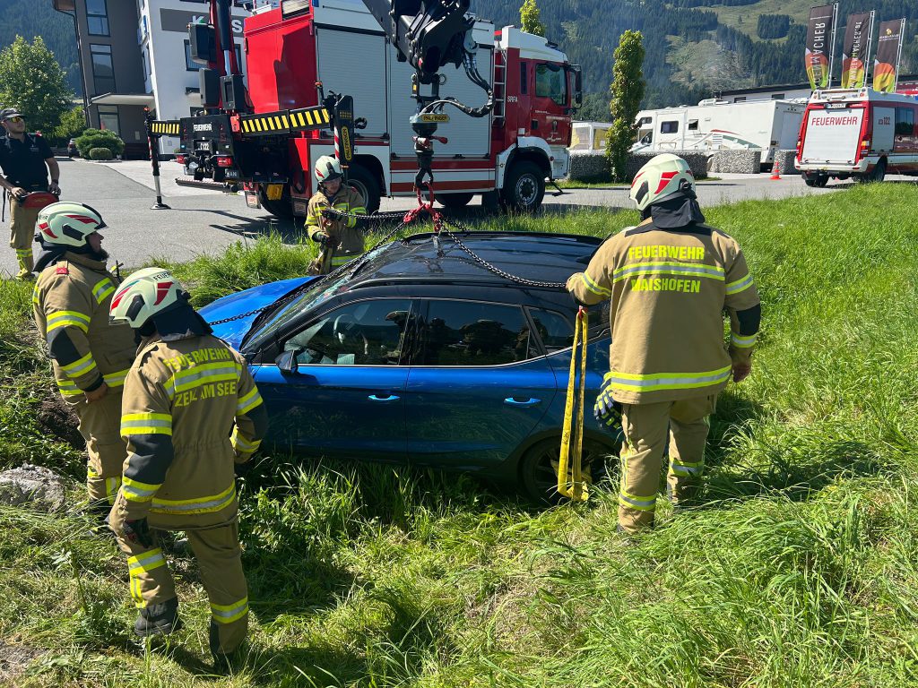 Feuerwehr sichert verunfalltes Auto mit Kran auf Wiese bei Verkehrsunfall Maishofen