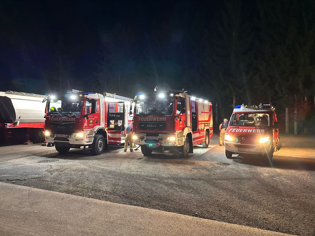 Drei Feuerwehrfahrzeuge bei nächtlichem Einsatz mit eingeschaltetem Frontlicht