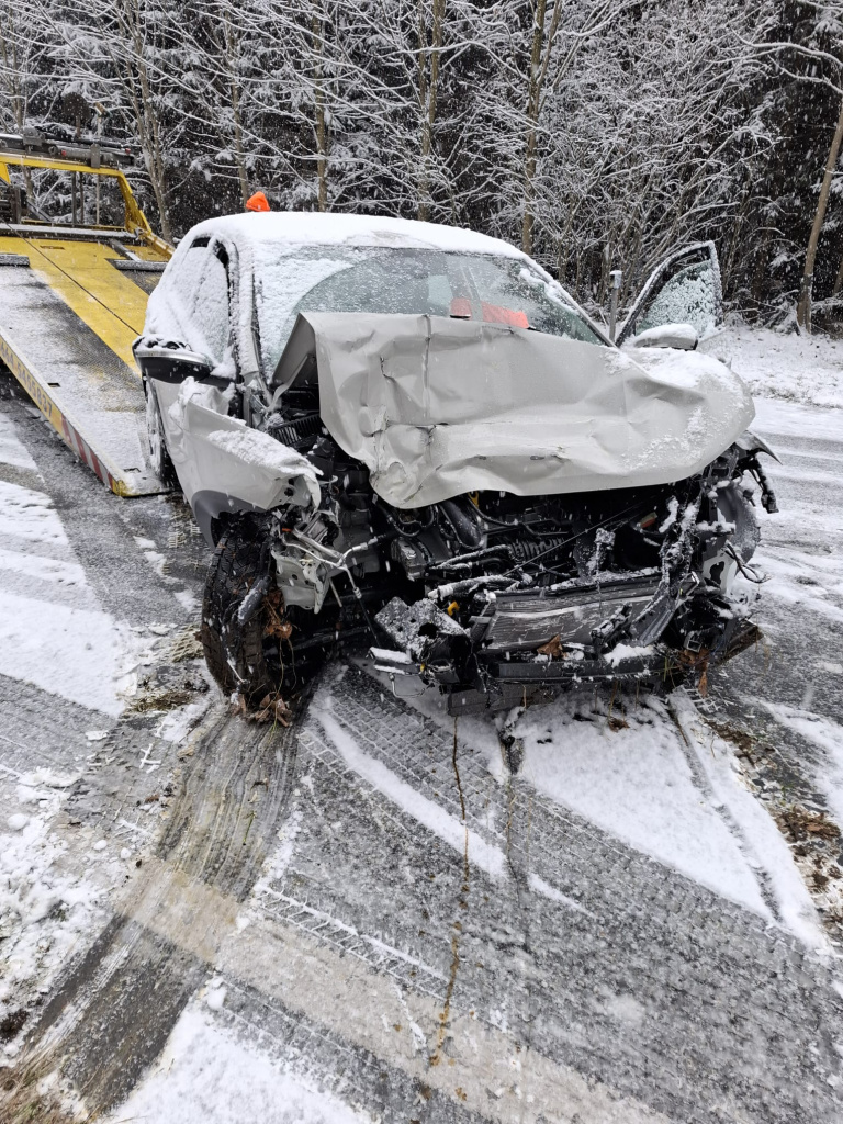 stark beschädigter PKW mit eingedrückter Front auf verschneiter Straße vor Abschleppfahrzeug