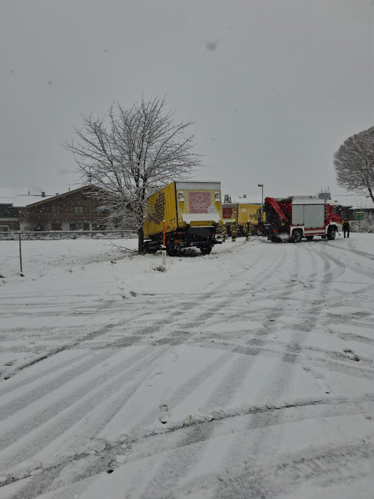 Feuerwehrfahrzeug und gelber LKW im Schnee bei einer Bergung
