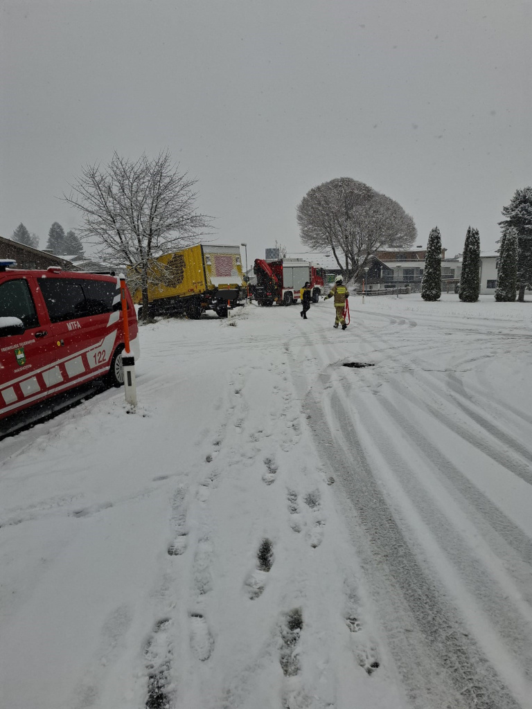 Feuerwehrkräfte bergen im Schneefall einen von der Straße gerutschten LKW