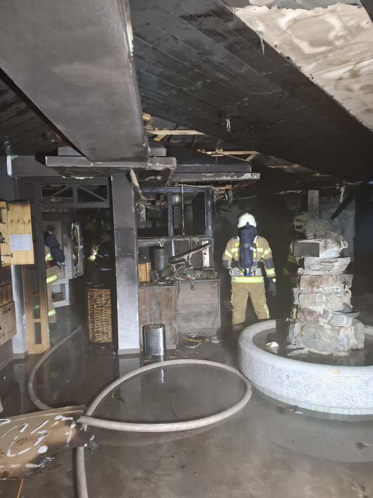 Atemschutzkräfte in verrauchten, beschädigten Innenräumen mit nassem Boden und Schläuchen