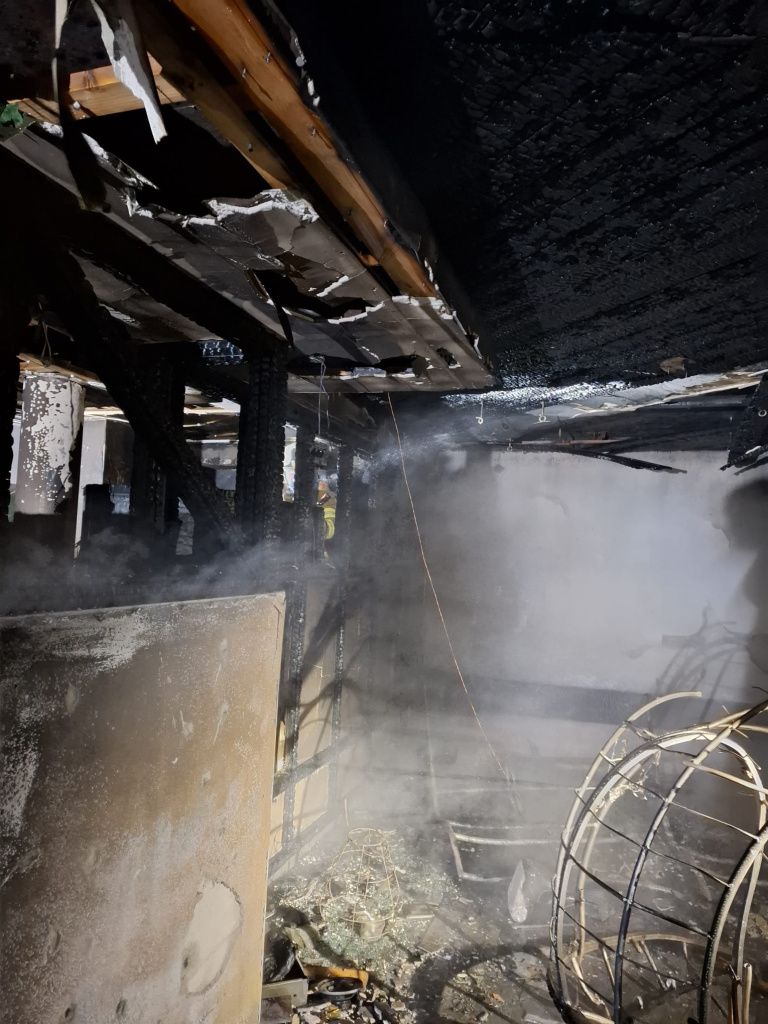 verbrannter Innenraum mit stark verrußter Decke, Schäden an Wänden und Rauchentwicklung